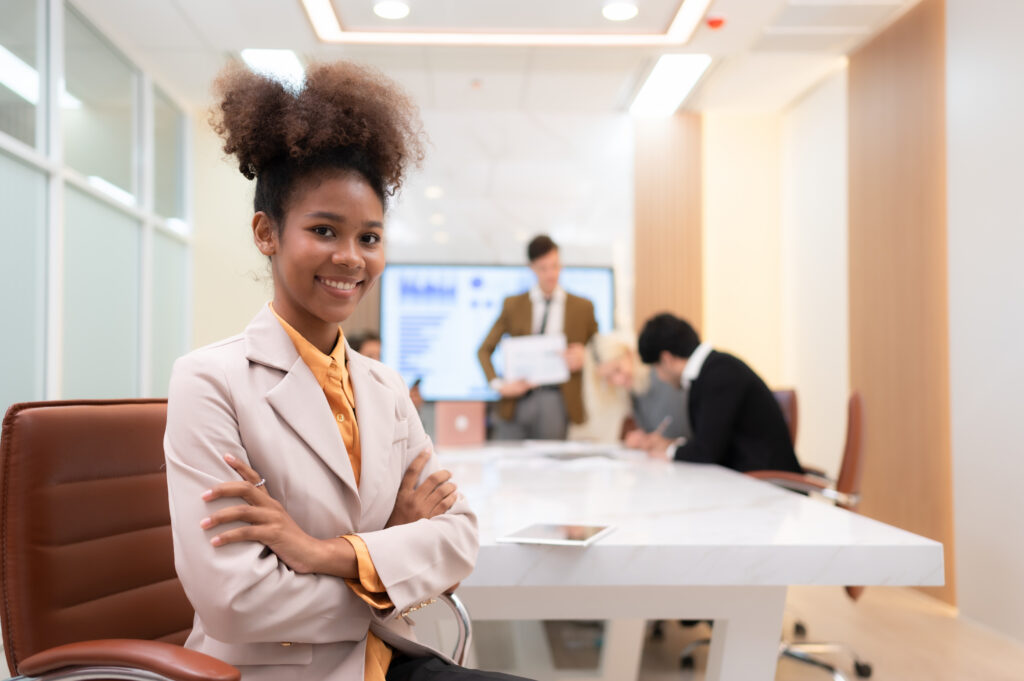 A young intern with her colleagues who are brainstorming in the background.